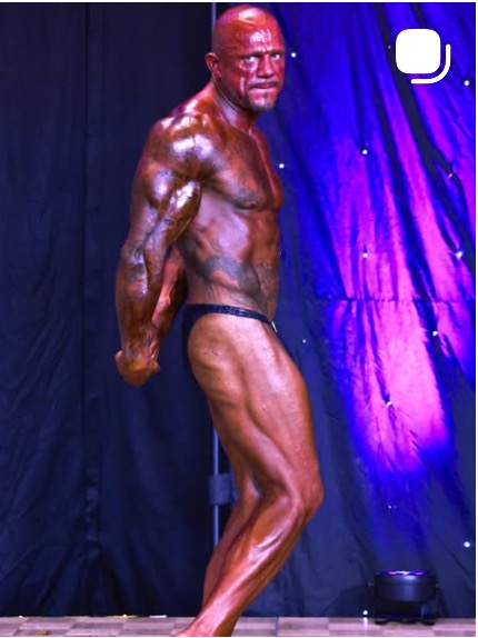 Coach Sam posing on a bodybuilding stage